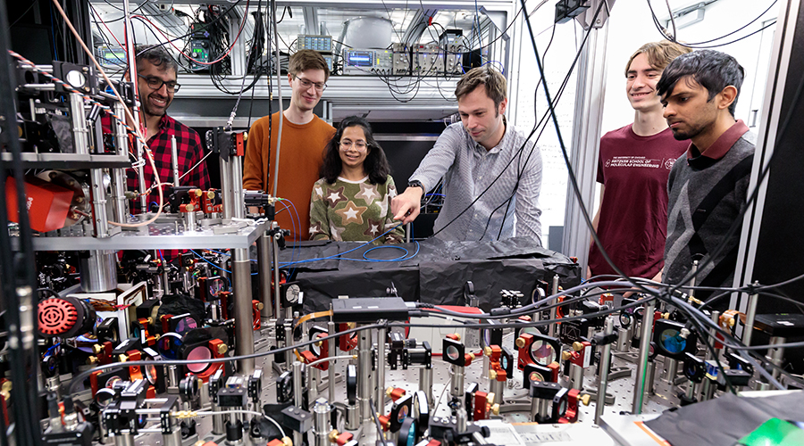 Hannes Bernien and lab members look at optical table