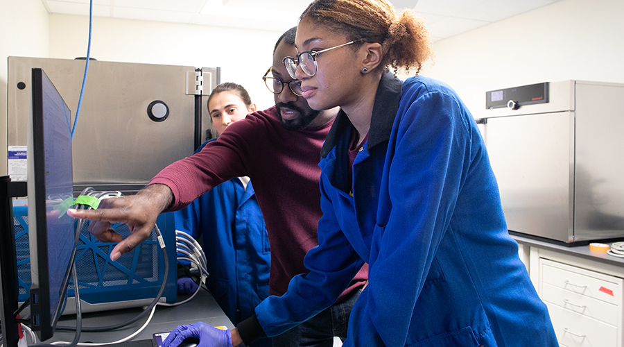 Briana Ross studies screen with Prof. Amanchukwu pointing to item