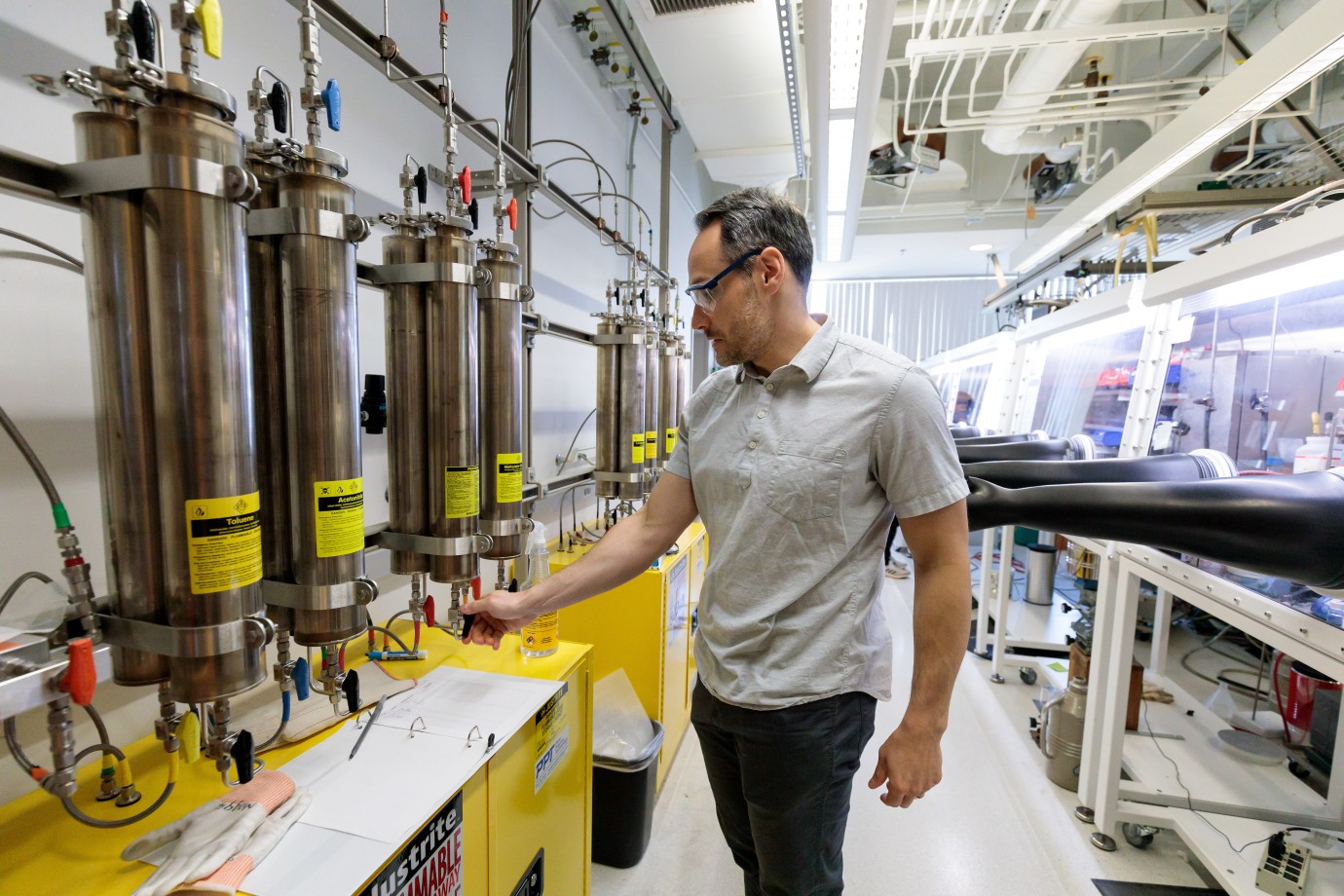 Man in light colored polo and safety glasses standing in lab