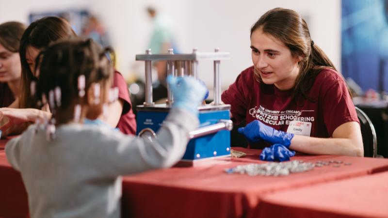 PhD student building a battery with a young child at a museum event