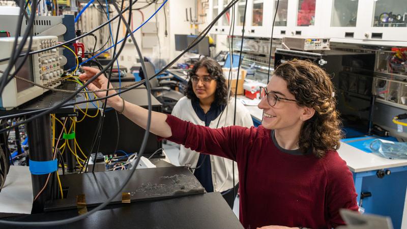 Two students work on optics table