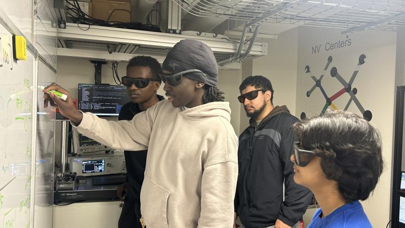 Students at a whiteboard doing quantum calculations