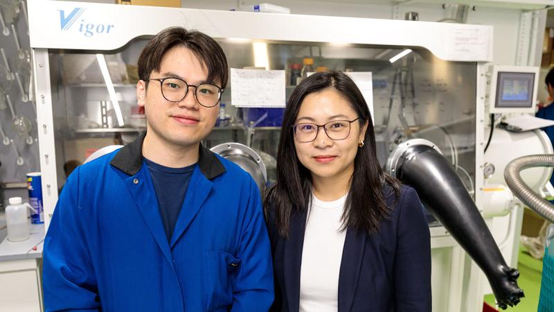 Two scientists stand in front of a laboratory glovebox