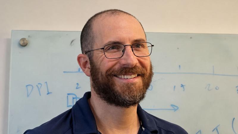 Man in glasses standing in front of whiteboard