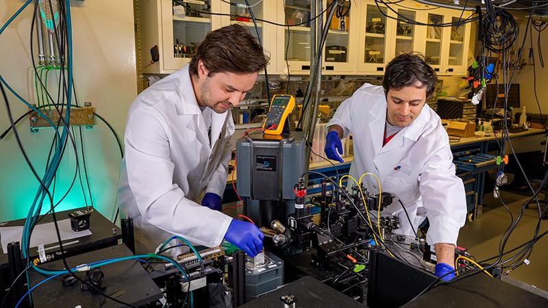 Two researchers working on an optics table