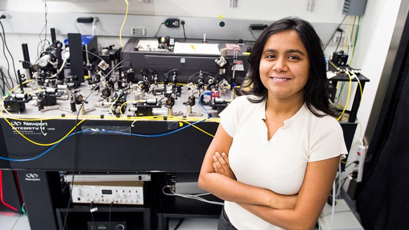 Student standing in front of optical table