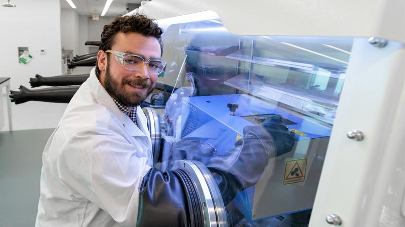 Scientist in lab coat with hands in scientific glovebox