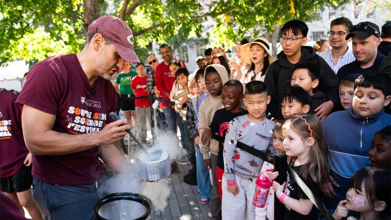 Scientist in South Side Science Festival T-shirt demonstrates steaming liquid nitrogen for group of children