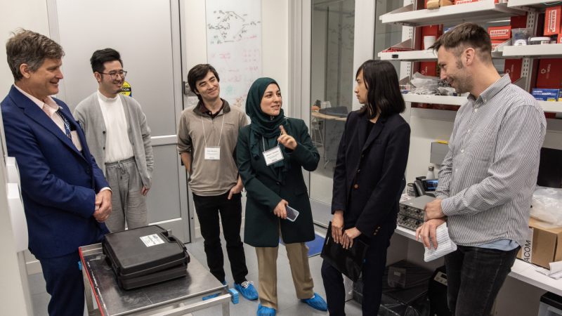 Group of men and women in suits conversing in lab