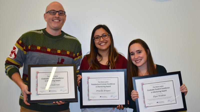 Three students holding framed certificates