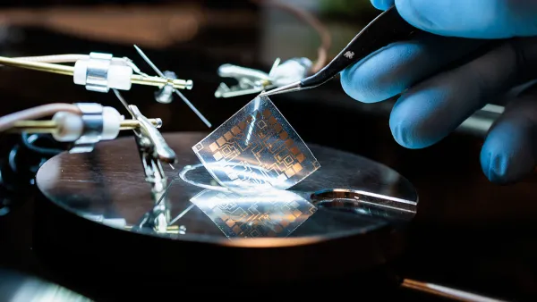 Gloved hand pulls adhesive semiconductor from plate