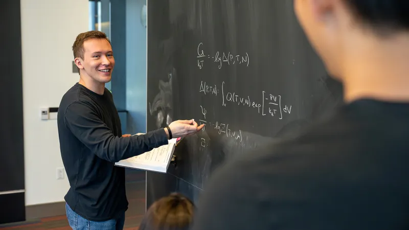 Student writes on blackboard