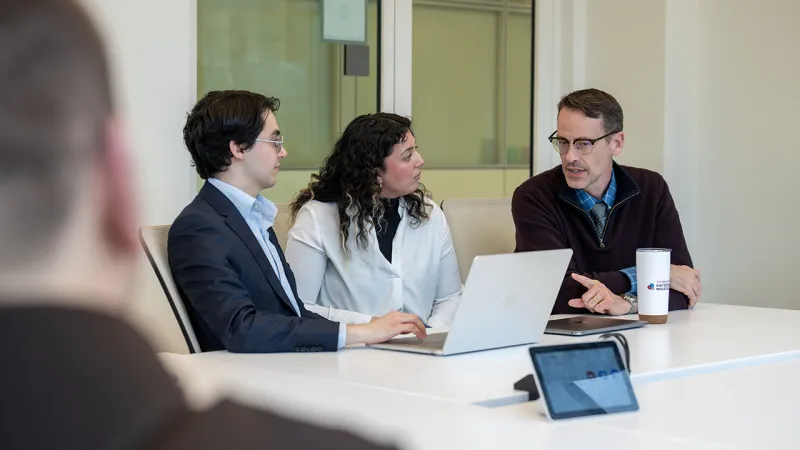 Faculty member and students sitting at conference table