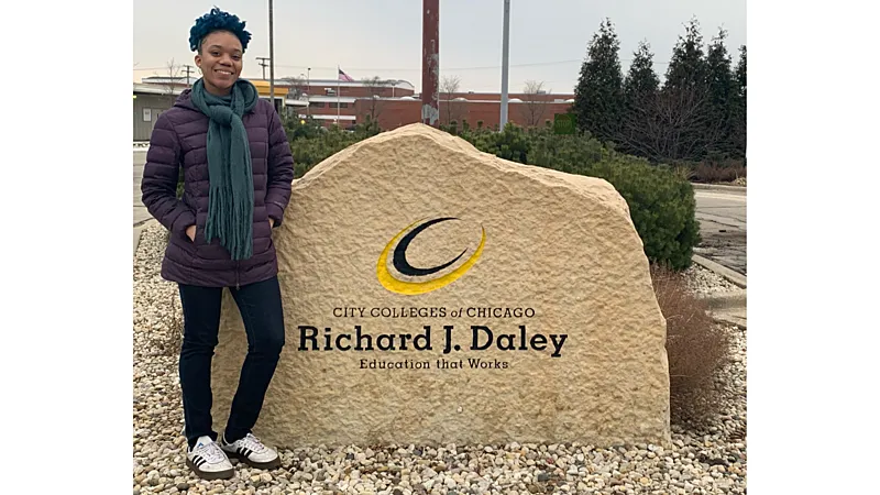 Destini Coleman standing in front of her college's sign
