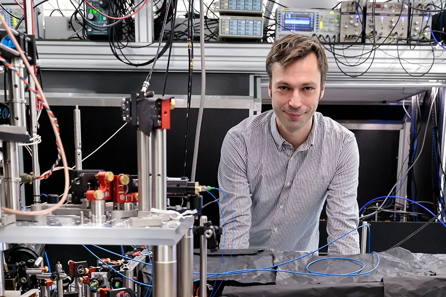 Hannes Bernien posing next to optical table