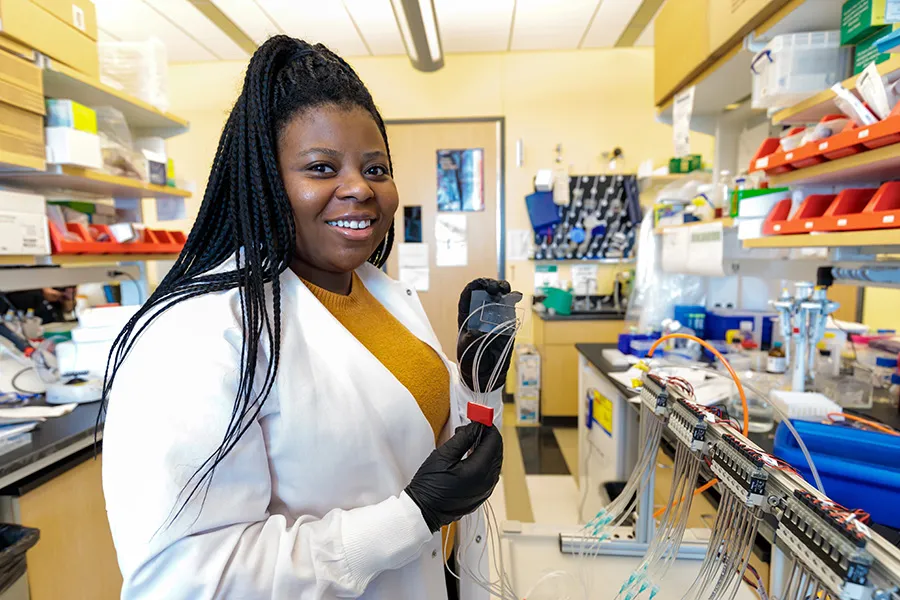 Susan Okrah holds up a microfluidic device