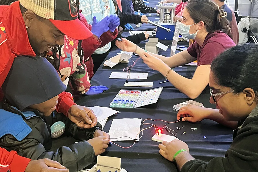 Table with volunteers and families doing battery demonstrations
