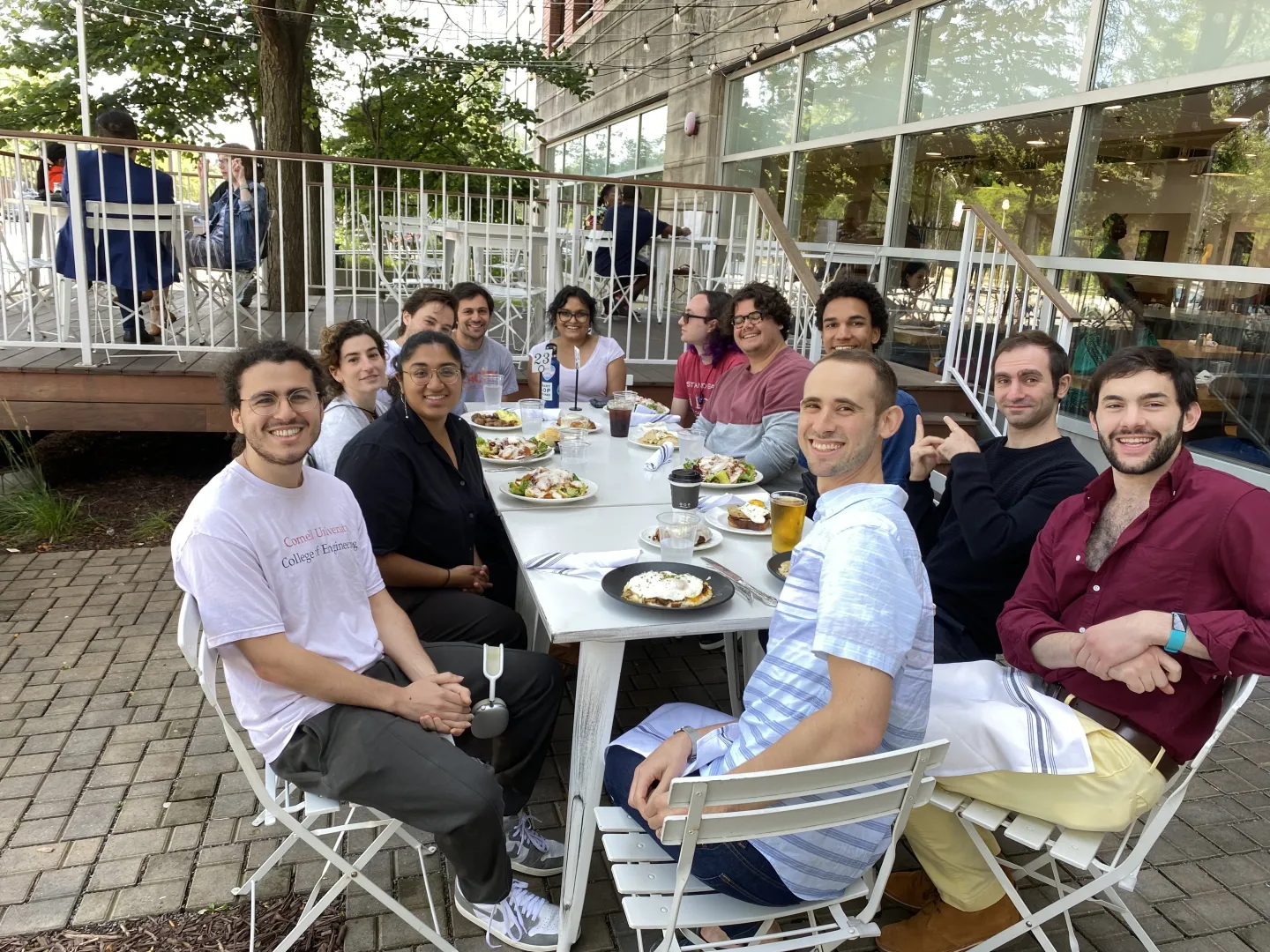 Graduate students and researchers gathered around an outdoor table for a casual group meal on campus.