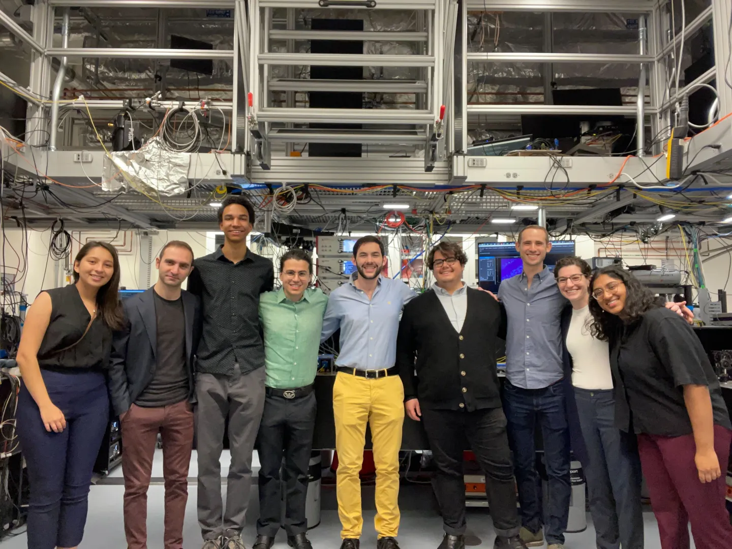 Research group posing together inside a nanofabrication laboratory surrounded by advanced scientific equipment.