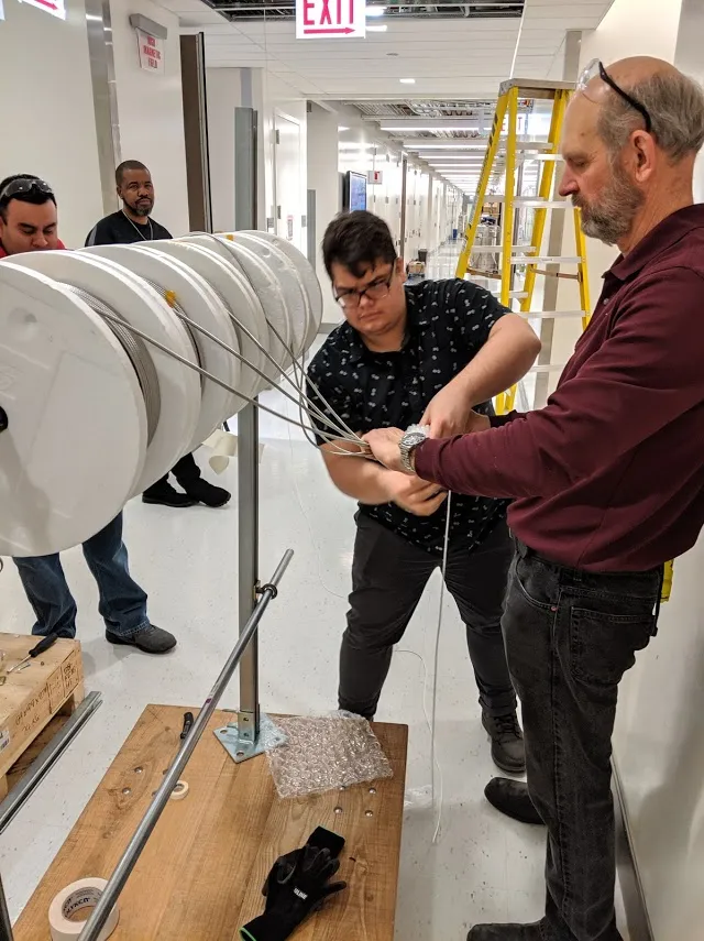Researchers assembling scientific equipment in a laboratory hallway during an experimental setup.