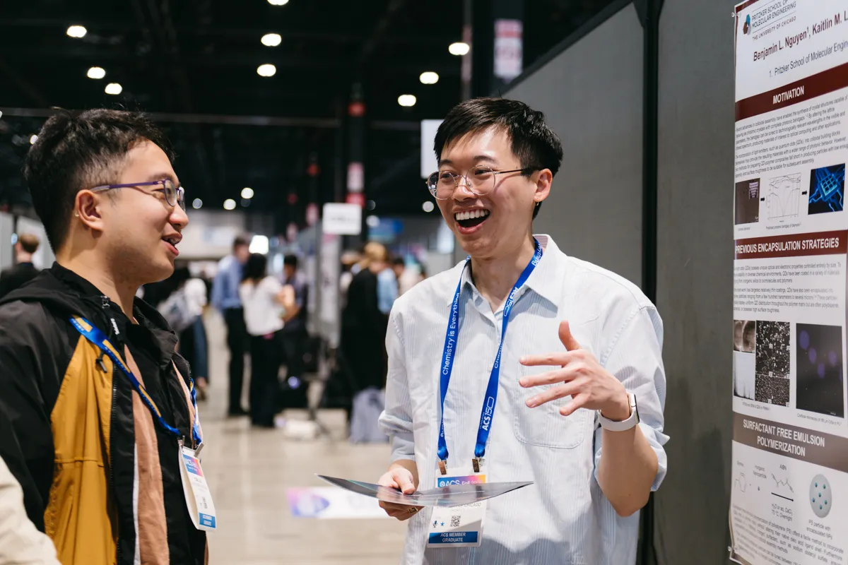 Two people chat next to research poster