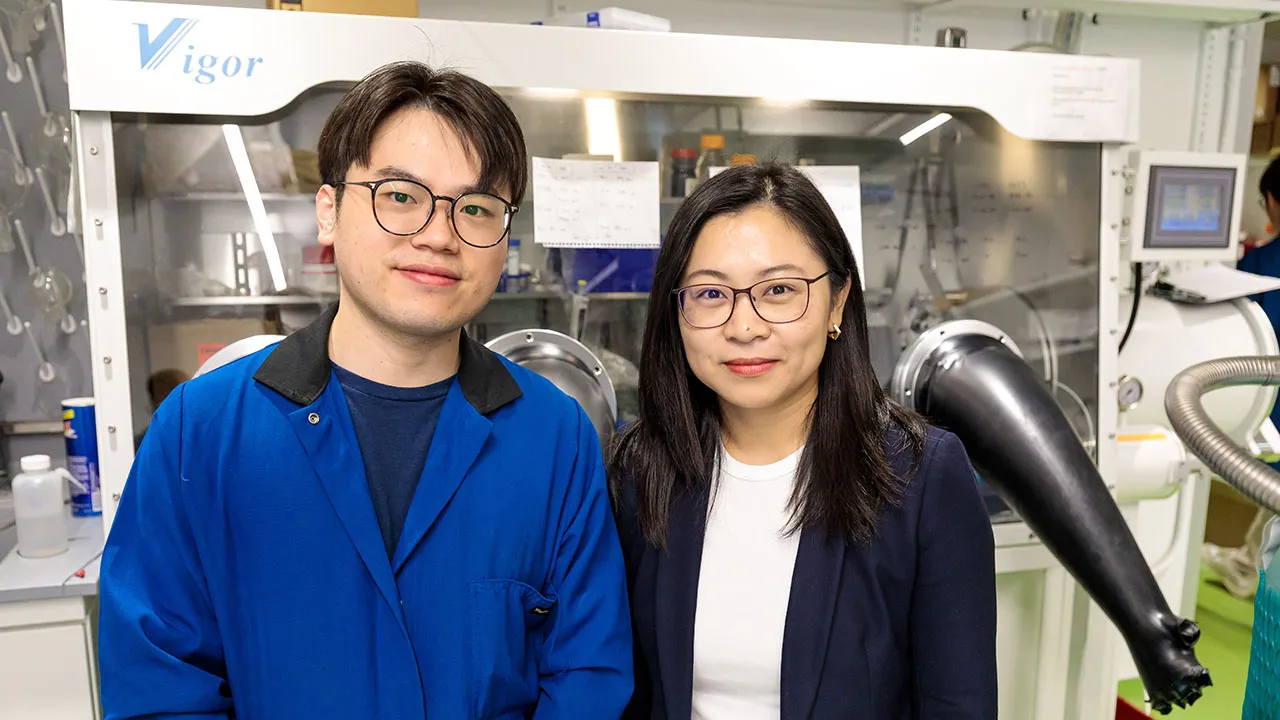 Two scientists stand in front of a laboratory glovebox