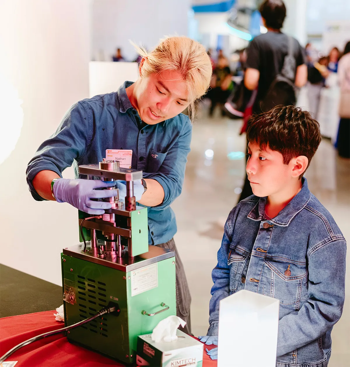 Fourth-year Molecular Engineering major Nathan Hu demonstrates the final step of building a battery. (Griffin Museum of Science and Industry / Jason Smith)