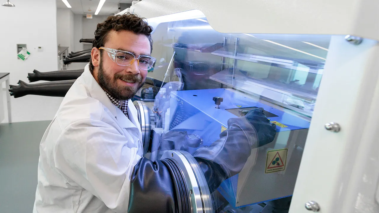 Scientist in lab coat with hands in scientific glovebox